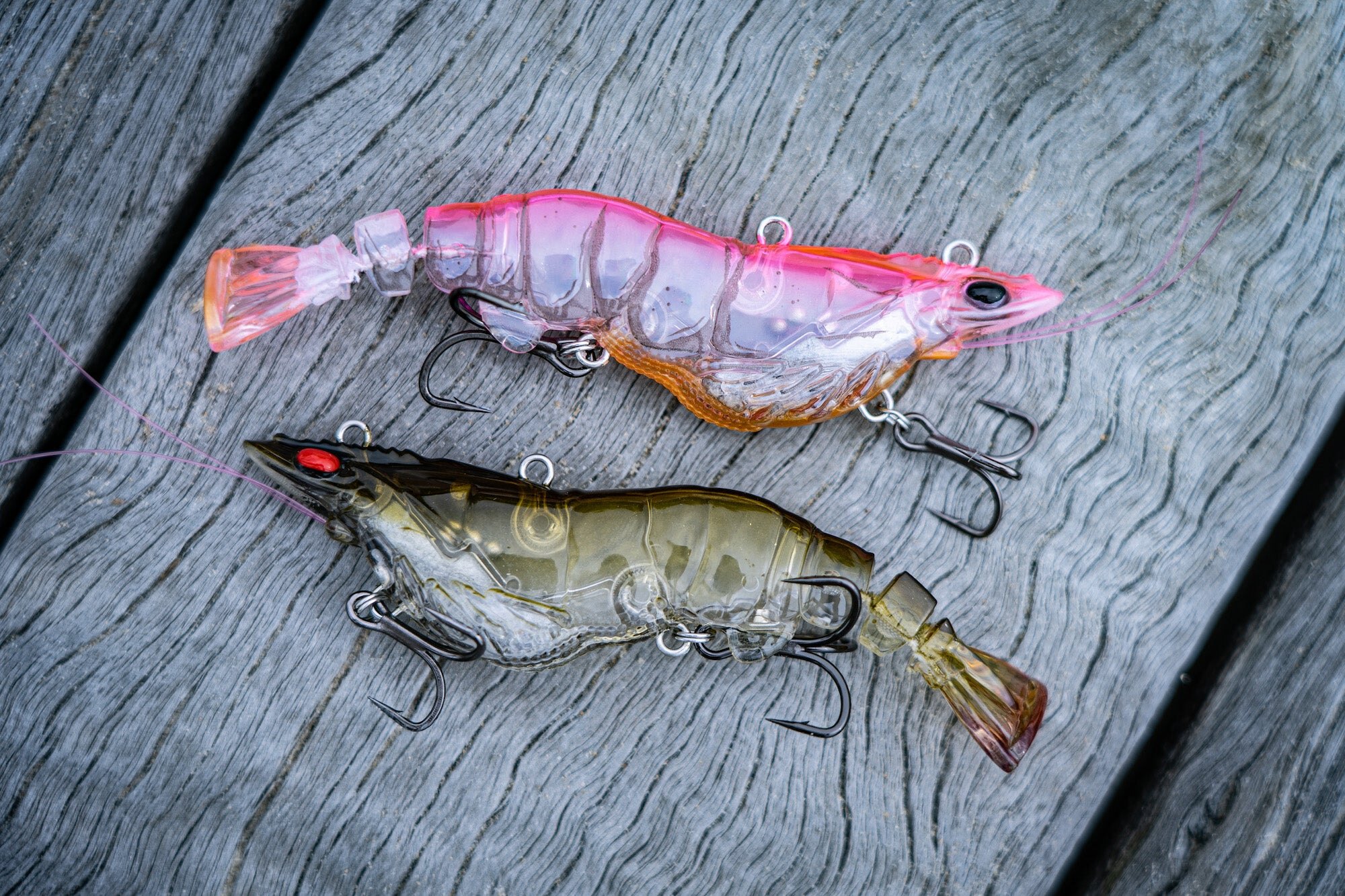 Two prawn lures on a weathered timber board